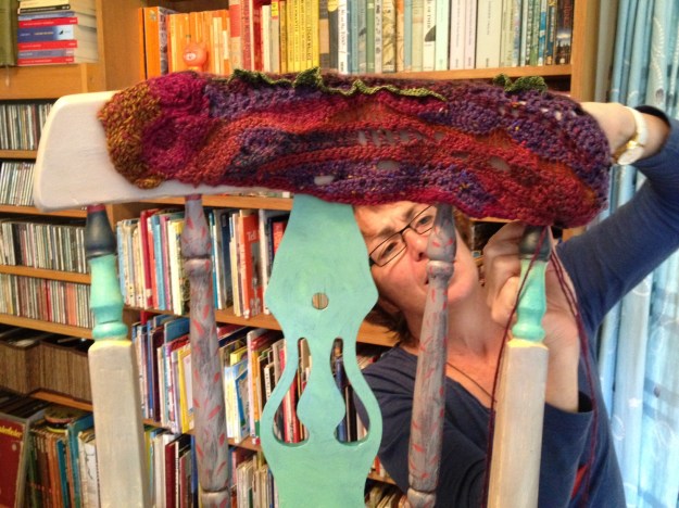 Kezzita in action. I'm loving those colours of wool and paint in front of the bookish backdrop :-)